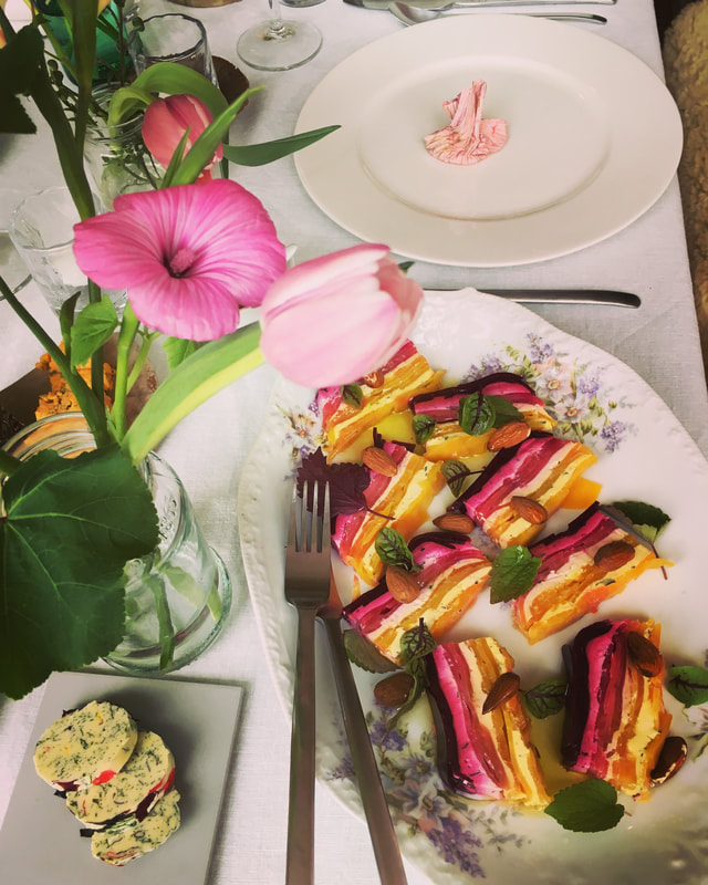 terrine van gepofte bieten met geitenkaas en tijm, bloemenboter, een vaasje met tulpen, amandelen, eetlandschap