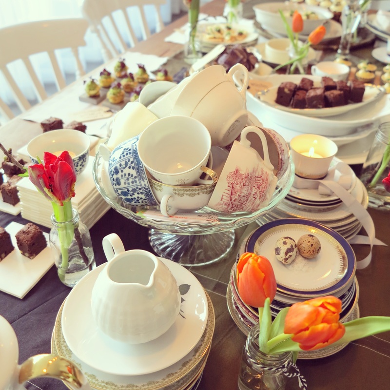 een high tea tafel met engelse kopjes en vaasjes met tulpen
