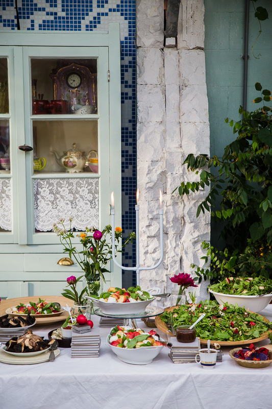 een mooi gedekte tafel met veldbloemen, salades, seizoensgerechten, mooi serviesgoed