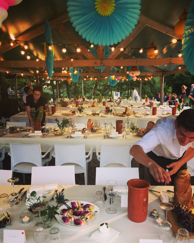 lange tafels gedekt voor een bruiloftsmaal met veldbloemen, broodtorens en huisgemaakte gerechten.