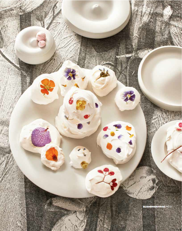 meringues met eetbare bloemen op prachtig tafellinnen en design serviesgoed